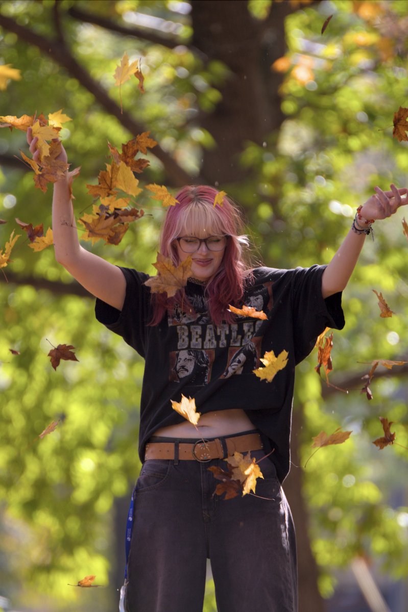 Finn Boggs stands in the fall of leaves during a photo walk. Photo walks are used to capture expressive moments on camera and video.