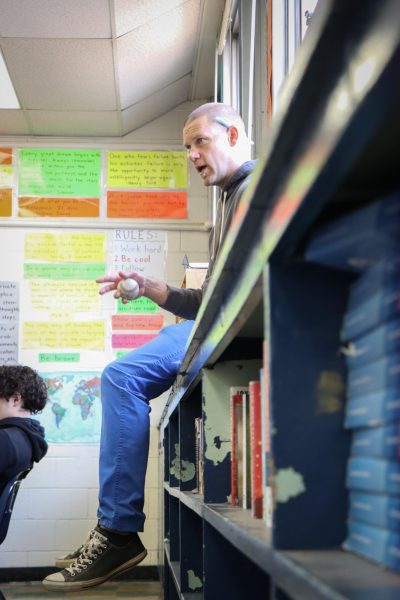 Brian Zurhellen sits on his bookshelf while teaching his philosophy class. Zurhellen's classroom is home to many books that have been historically deemed "controversial."